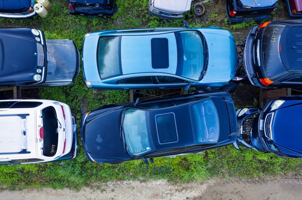 High-angle shot of abandoned cars in a junkyard, showcasing diverse vehicle models in Red Wing, MN.