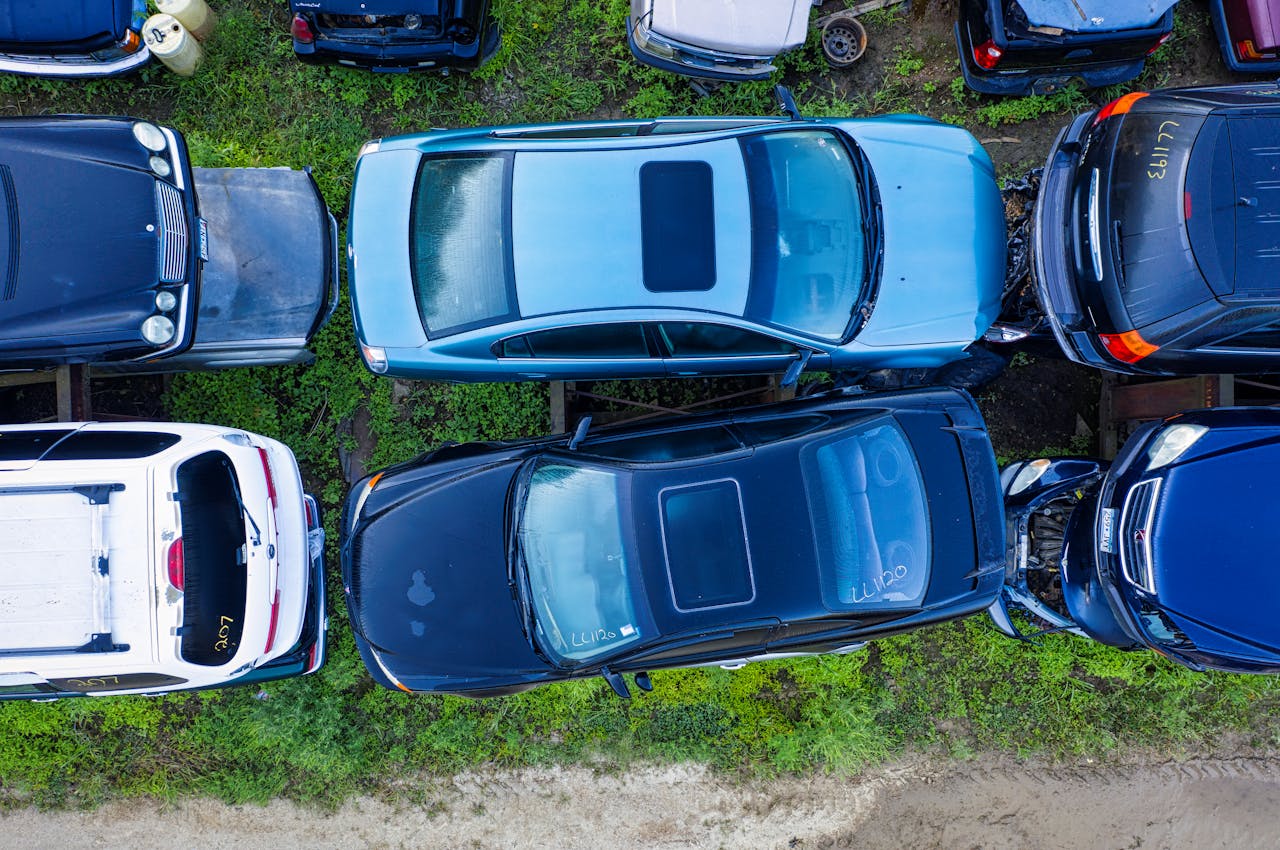 High-angle shot of abandoned cars in a junkyard, showcasing diverse vehicle models in Red Wing, MN.